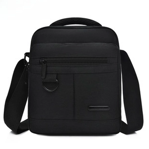 Front detail of black men's canvas shoulder bag with zipper pocket and metal D-ring