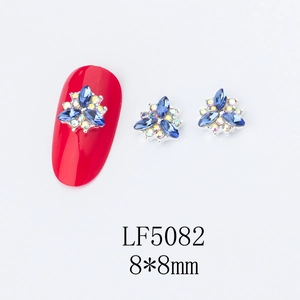 Close-up of 8mm flower nail art charm with blue rhinestones on a red manicure