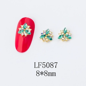 Macro detail of 3D flower nail art charms with green marquise gems and gold setting