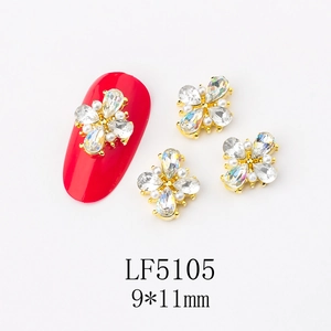 Detail of 9x11mm flower nail charm with gold base and rhinestones on red nail tip