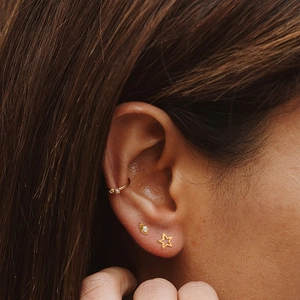 Close-up of gold hollow star stud earrings and ear cuff set with pavé cubic zirconia