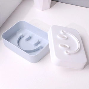 Dual-layer smiley face soap dish with blue base and white drainage tray in plastic