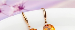 Detailed macro shot of gold earrings with oval yellow citrine and clear diamond accents