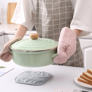 Pink quilted cotton oven mitt and potholder set used for handling a hot ceramic pot