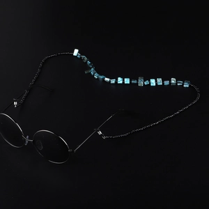 Minimalist sunglasses chain with black beads and blue shell pieces on dark background
