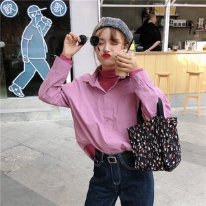 Dettaglio di una borsa tote in velluto a fiori abbinata a una camicia rosa morbida