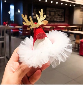 Close-up of a Christmas hair clip featuring red hat, golden reindeer antlers and tulle