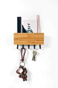 Wall-mounted bamboo key holder detail with five black metal hooks and mail storage slot
