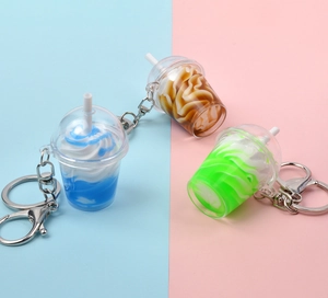 Trois mini porte-clés gobelets colorés avec garniture crème sur un fond bicolore