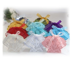 Laser-cut shell candy boxes with ribbons for weddings, shown in multiple colors and patterns
