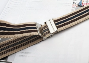 Detail view of adjustable elastic belt with tricolor stripes and metal buckle