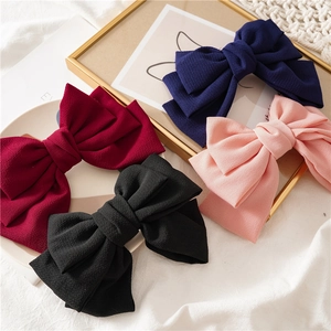 Detailed view of layered fabric bow hair clips in navy, pink, burgundy and black