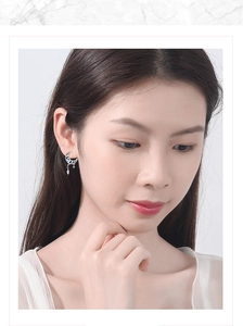Detailed view of silver moon tassel earrings with blue gemstones worn on ear