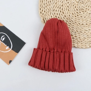 Detail view of a brick red ribbed knit beanie for children with soft warm texture