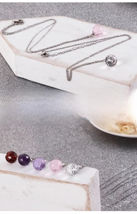 Detailed close-up of faceted crystal sphere pendants on titanium steel chain necklaces