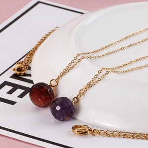 Detail of faceted purple and amber glass crystal pendants on gold titanium steel chains