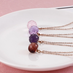 Close-up of faceted crystal ball pendants in four colors on rose gold chains