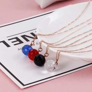 Close-up of multi-faceted crystal necklaces in blue, red, black, and clear on a white tray