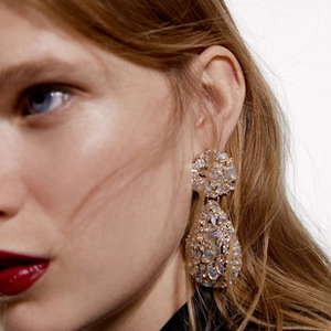 Close-up of luxury gold skull earrings with iridescent rhinestones on a female model