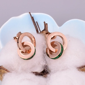 Detail of rose gold interlocking double ring earrings with Roman numerals and green gems
