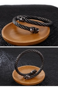 Detail eines Retro-Edelstahl-Kabelarmbandes mit gotischen Totenkopf-Endstücken
