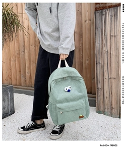 Detail of mint green corduroy backpack with cartoon eye decor and embroidered patch