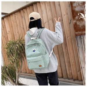 Detail of mint green corduroy backpack with cute eye embroidery shown on back