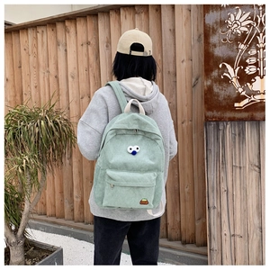 Outdoor shot showing back view of mint green corduroy backpack with cute cartoon accents