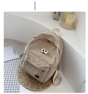 Detail view of the khaki corduroy backpack with cute eye embroidery in a lifestyle setting