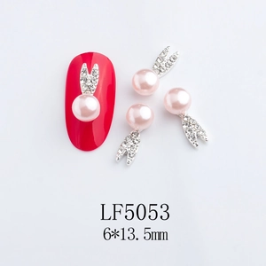 Detail of pink pearl rabbit nail charms with rhinestones shown on a red nail tip