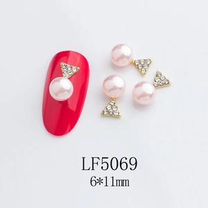 Close-up of pink pearl and gold star nail art charms on a manicured red nail detail