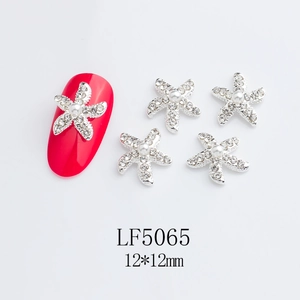 Macro shot of 12x12mm starfish nail charms with pearls and rhinestones on a red nail
