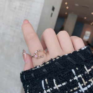 Detail of rose gold open ring with pink stone and white cubic zirconia on finger