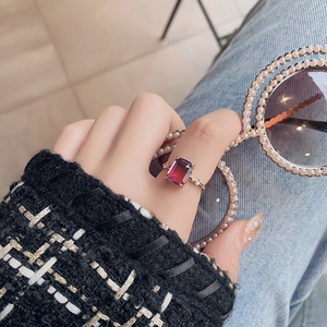 Detail of rose gold ring with gradient purple zircon on a model holding pearl sunglasses