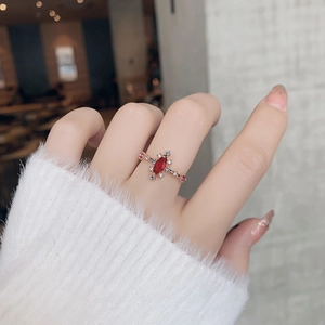 Detail shot of a rose gold flower ring with marquise red gem and colorful crystals