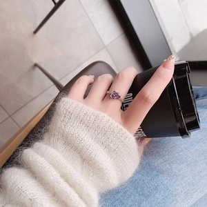 Detail of luxury crystal flower ring with purple gemstones on woman's hand with coffee