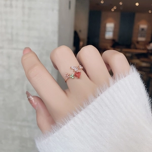 Close-up of rose gold ring with red heart and clover gems worn by a model