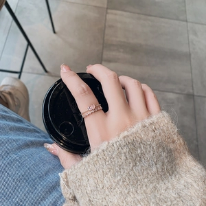 Close-up of rose gold ring set with pink pear-cut stone and pavé band on finger