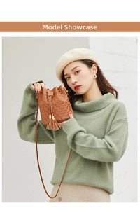 Sac seau marron à motifs gaufrés et glands, porté par un mannequin en pull vert d'hiver
