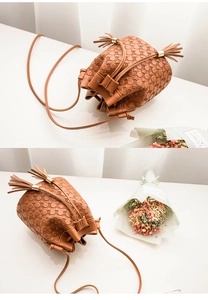 Détail du sac seau marron avec texture à pois et cordon de serrage à double pompon