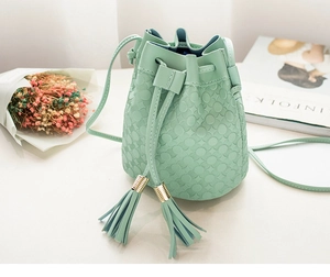 Détail d'un sac seau vert menthe avec gaufrage floral et pompons élégants en cuir PU