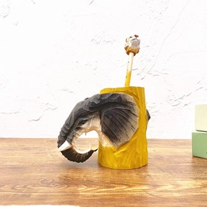 Détail d'un porte-stylo en bois sculpté avec tête d'éléphant et crayon à tête de tigre