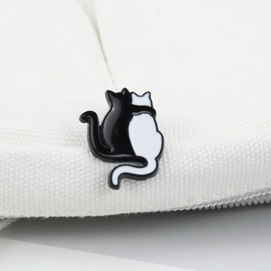 Enamel black and white cat hug brooch badge pinned on white canvas background