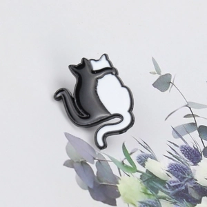 Detailed view of yin yang cat enamel pin with black and white kittens and floral decor