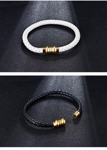Detail of white and black braided leather bracelets with gold magnetic clasps on black texture