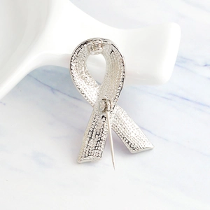 Back view of silver ribbon brooch showing textured metal surface and secure pin closure