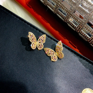 Macro shot of butterfly earrings with pink rectangle gemstones and golden base detail