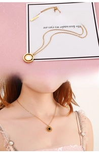 Macro di una collana in oro rosa con pendente a numeri romani e intarsio in madreperla