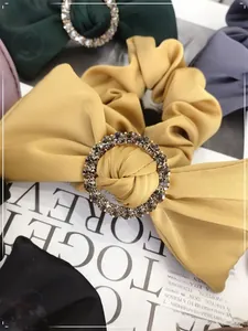 Close-up of yellow scrunchie with sparkling crystal ring buckle and soft pleated fabric