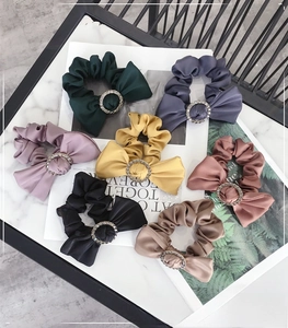 Detail view of seven colorful satin bow scrunchies with elegant rhinestone buckles
